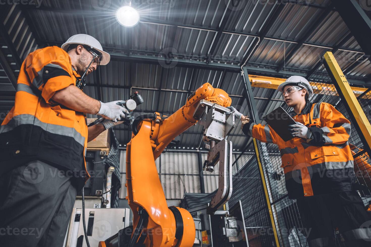 Engineer team service robot welding working in automation factory. People worker in safety suit work robotic arm software programming or replacing part in automated manufacturing industry technology. photo