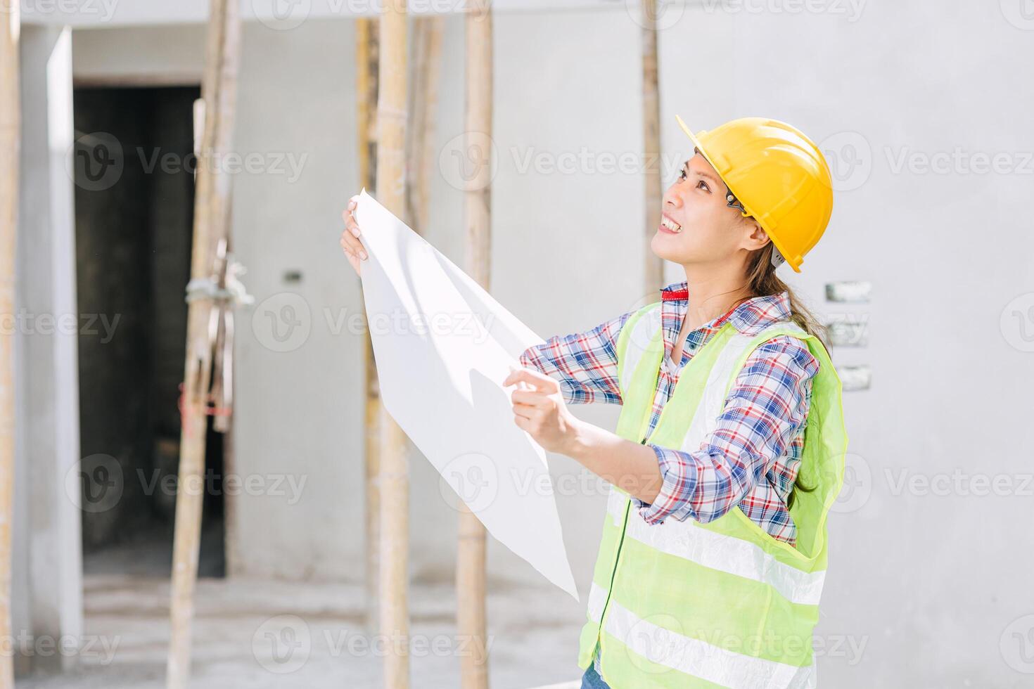 Asian woman engineer worker work in construction site. Smart builder architect female in safety suite working. photo