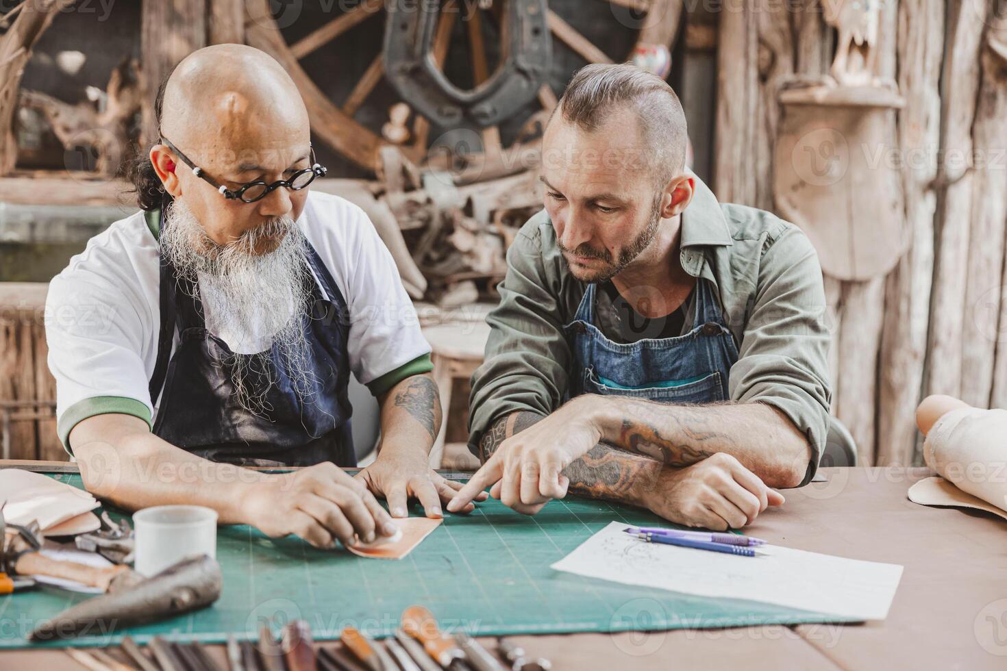 master of leather tailor teaching and training young man for making handcraft leather pouch photo