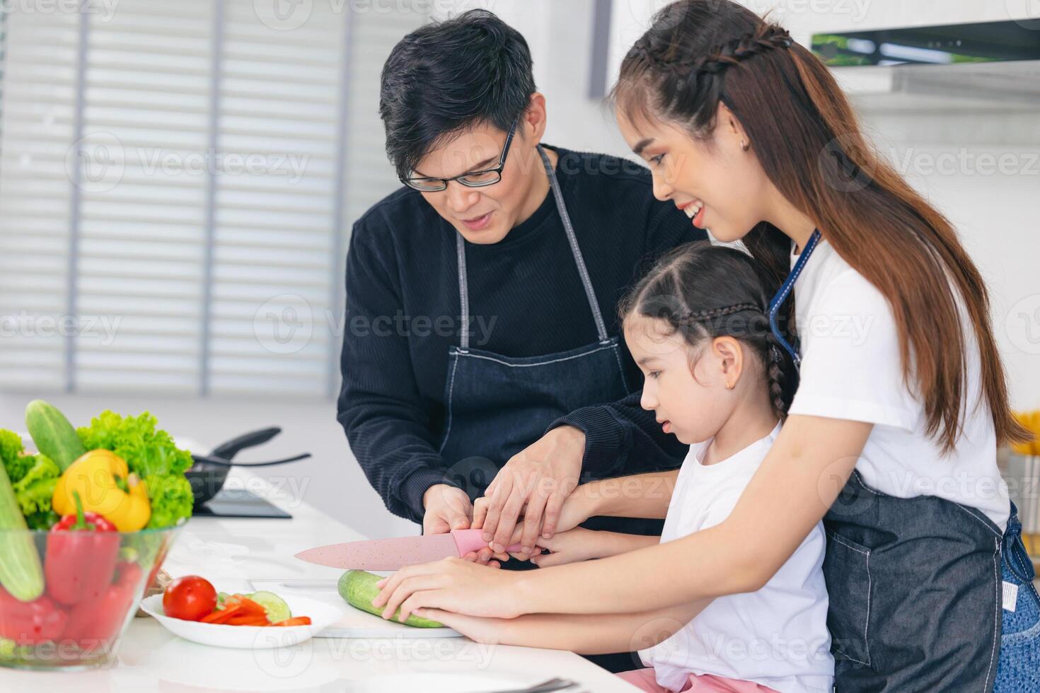 Child playing cook food with father and mother at home kitchen. Asian family happiness moment together. photo