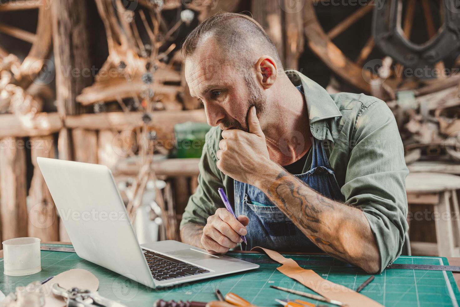 cuero artista hipster mirando a computadora ordenador portátil pantalla grave pensando para aprendizaje o contacto cliente foto