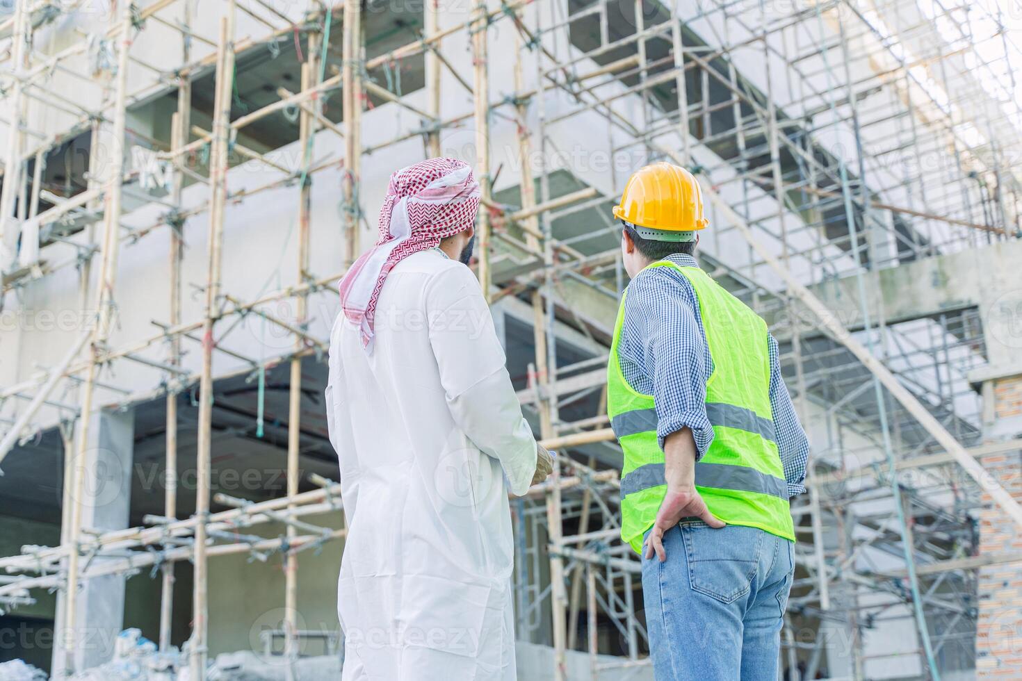 engineer standing with arub property investor looking under construction building for new properties  projects in middle east country photo