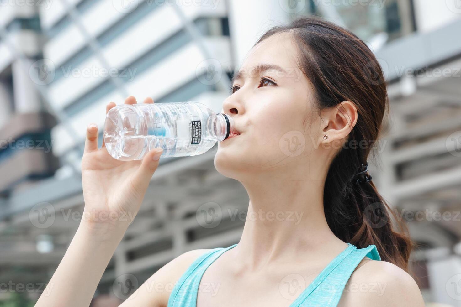 Asian lady drinking water sport healthy lifestyle outdoors in building city background photo