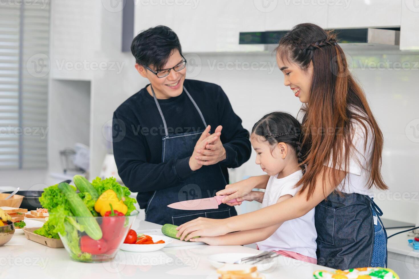 Child playing cook food with father and mother at home kitchen. Asian family happiness moment together. photo