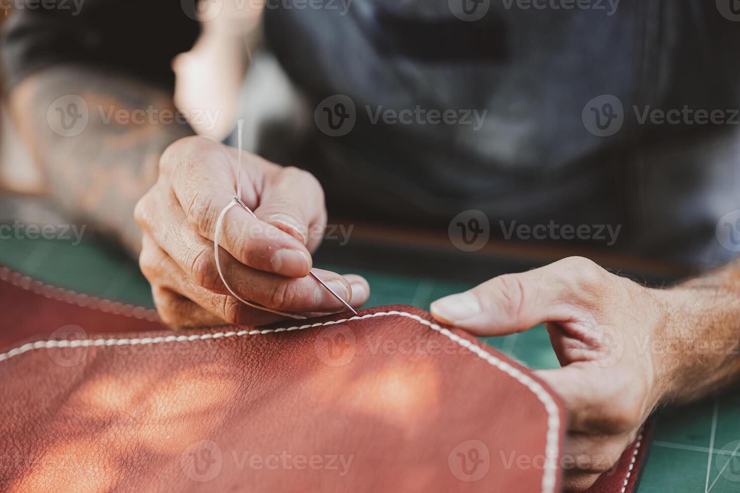 closeup hand working process leather handcraft in the leather workshop. Man holding crafting tool and working. He is sewing hammer to make a wallet. Tanner in old tannery. photo