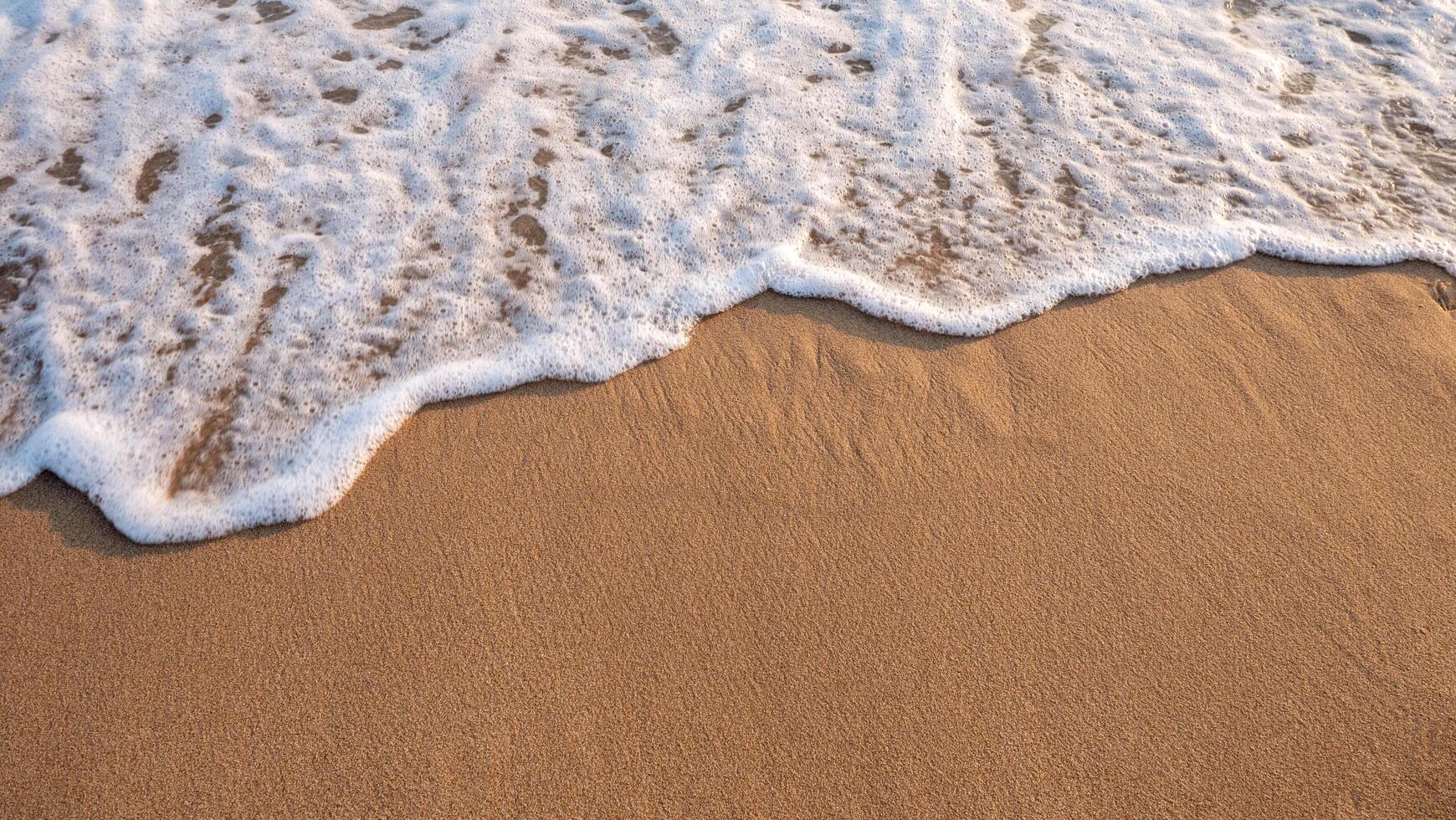 White foamy background of waves crashing on a sandy beach. photo