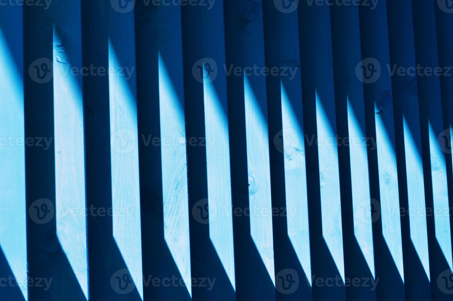 Beautiful wooden blue slats. A streak of sunlight on a wooden fence. Bright abstract background. Element of finishing the facade of the building. photo