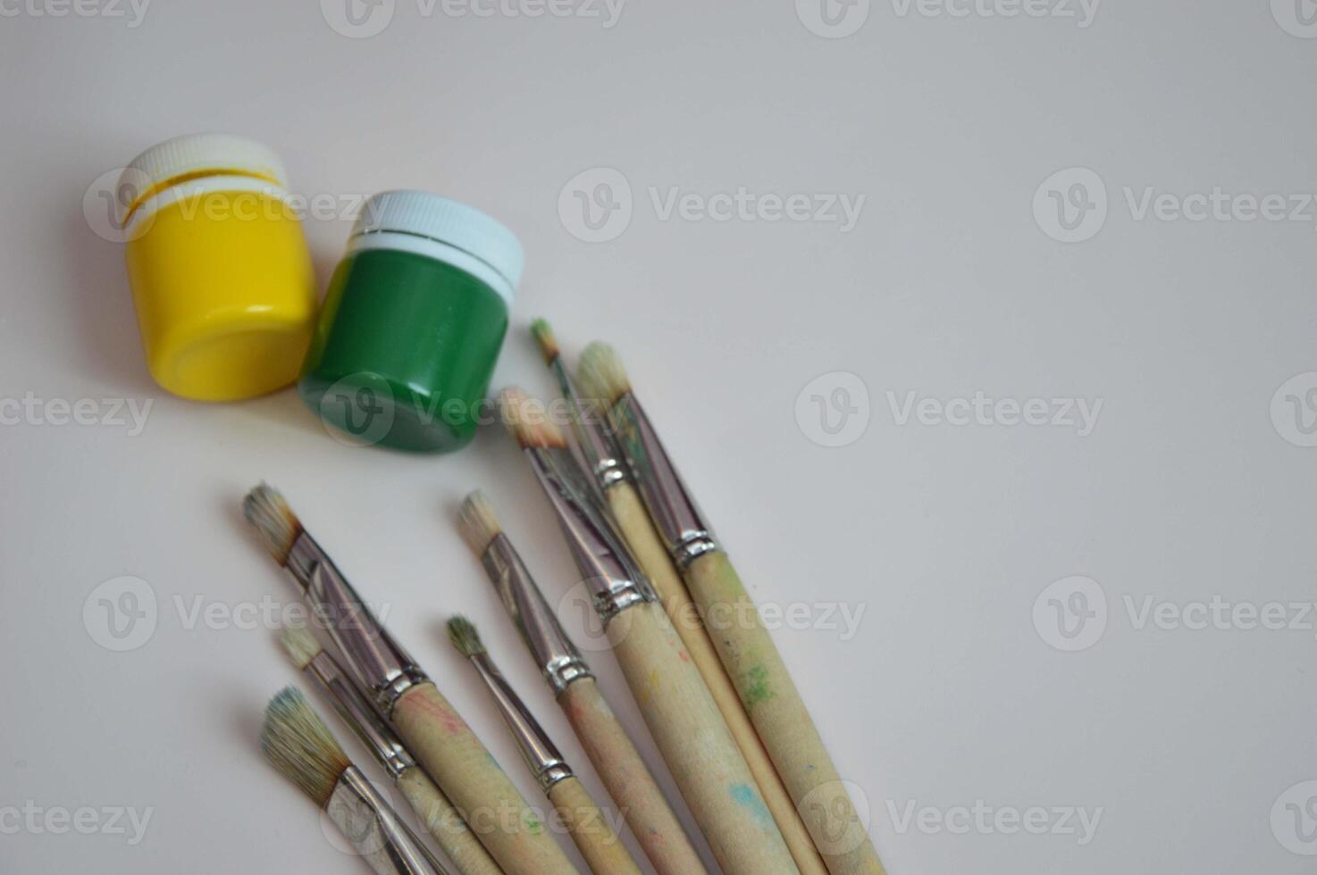 Jars of closed gouache paints and brushes on a white background. Items for drawing, creativity, hobby. photo