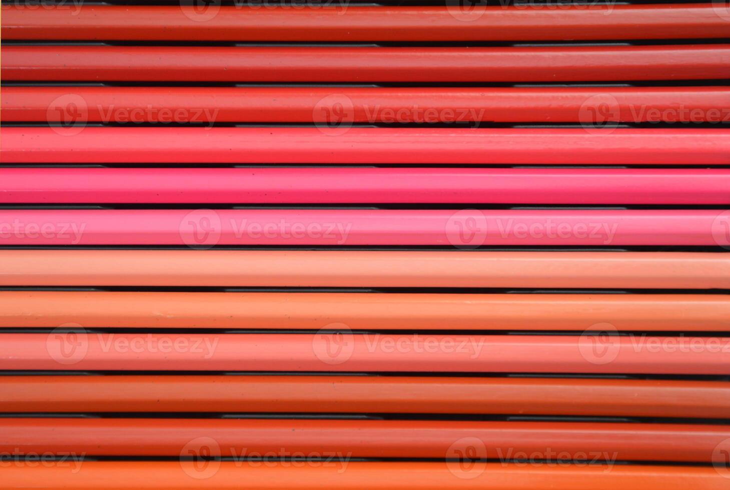 A set of Colored pencils lying in a beautiful gradient transition from yellow to pink and red, brown and purple hues. Abstract background. photo