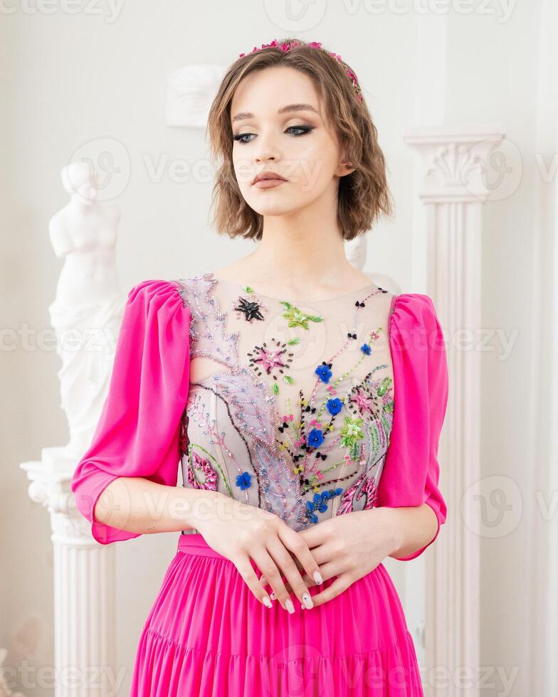 A girl with short hair and a pink dress with a flower crown on her head photo