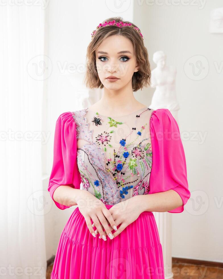 A girl with short hair and a pink dress with a flower crown on her head photo