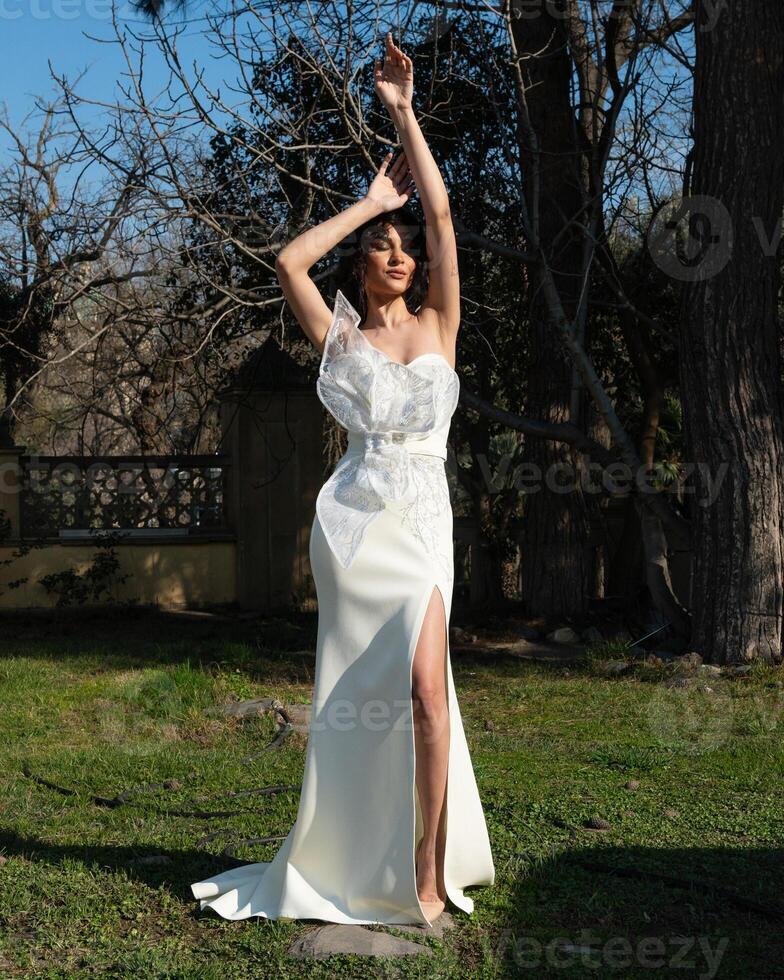 A woman in a white dress stands in front of a house. photo