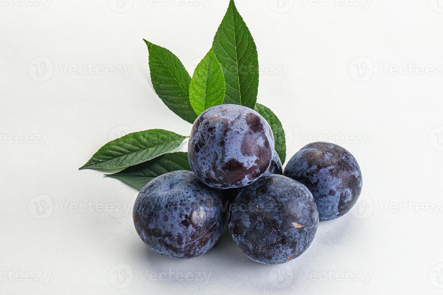 Raw purple plums heap with leaves photo