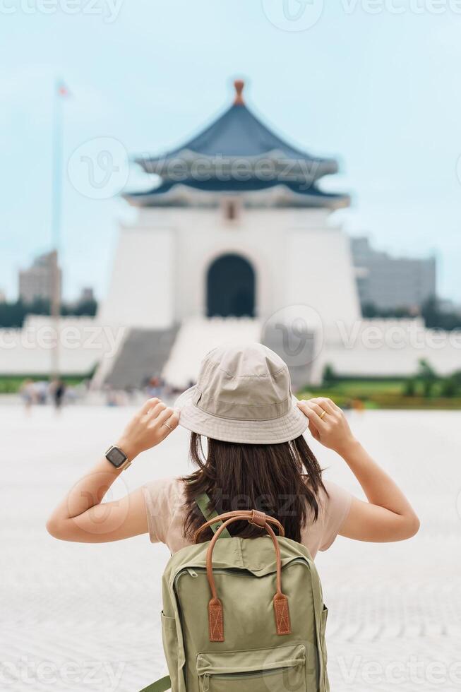 woman traveler visiting in Taiwan, Tourist with backpack sightseeing in National Chiang Kai shek Memorial or Hall Freedom Square, Taipei City. landmark and popular attractions. Asia Travel concept photo