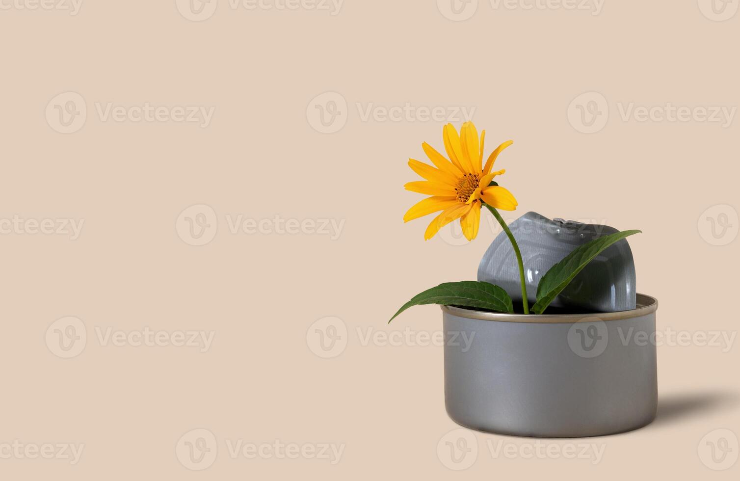 A flower in a metal jar on a beige background. Environmental pollution. Ecology concept. Earth pollution. Copy space. photo