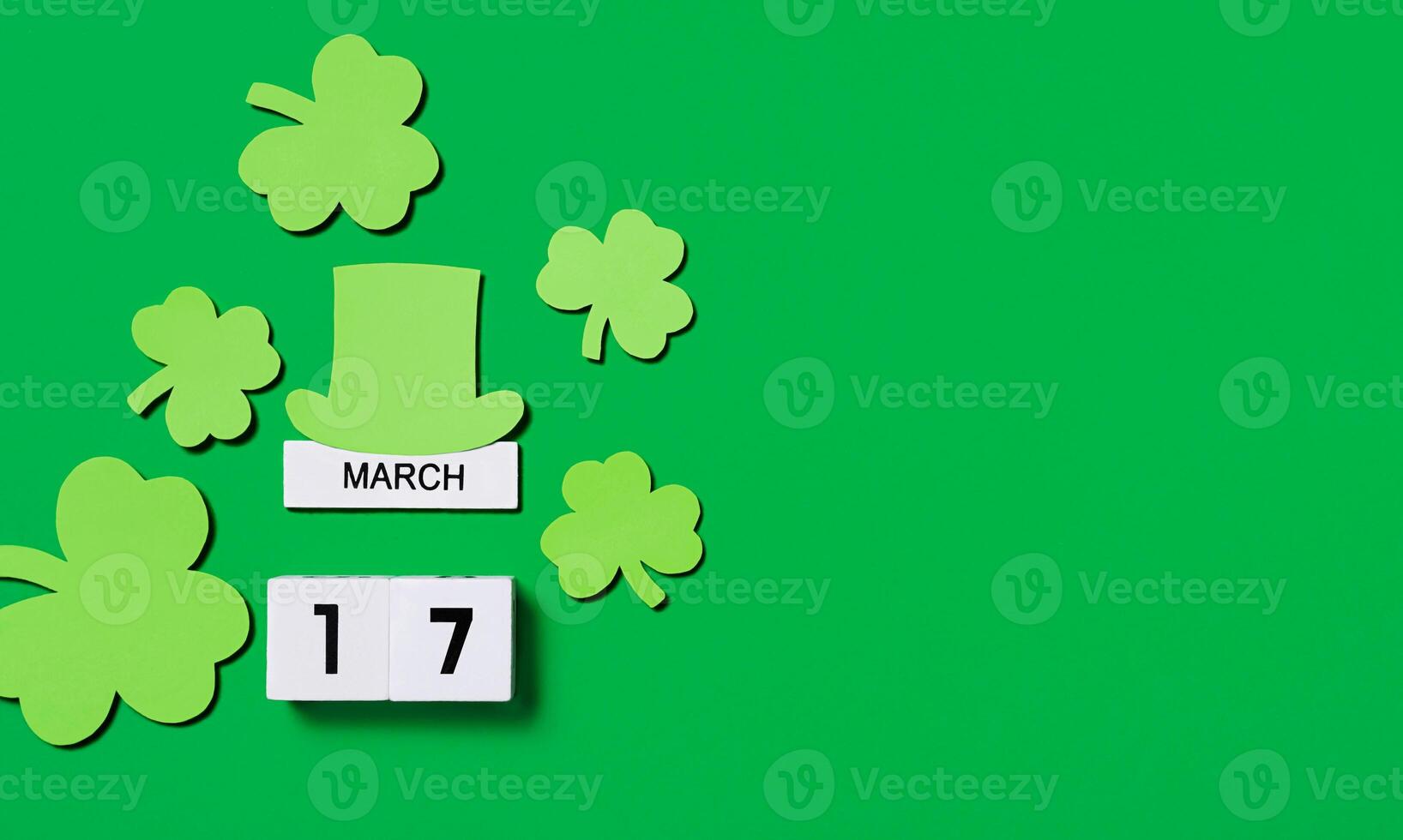 St. Patrick's Day concept. Wooden calendar with shamrocks and gnome's hat on a green background. banner Copy space. photo