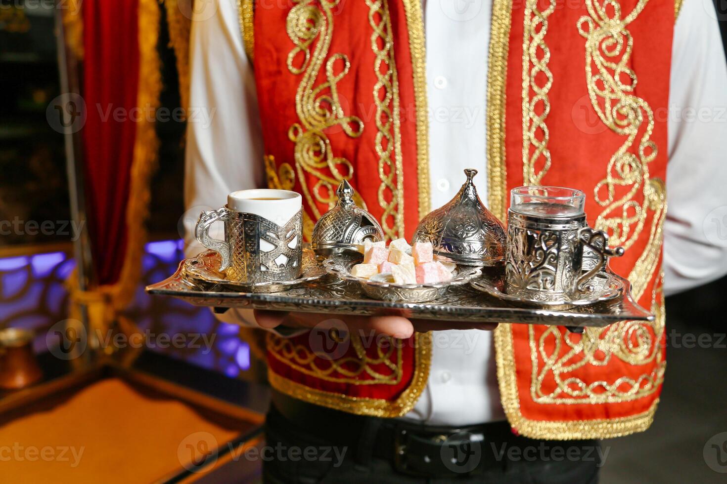 Man in Red Vest Holding Tray With Silver Cups photo