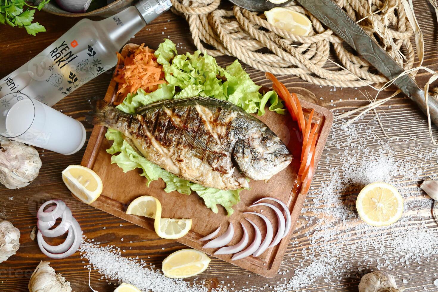 Freshly Caught Fish on a Wooden Cutting Board With Sliced Lemons and Garlic. photo