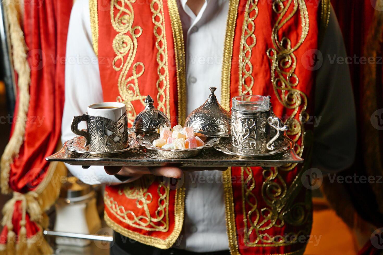 Man in Red Vest Holding Tray of Tea photo