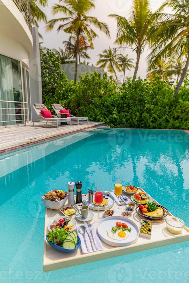 desayuno en piscina, desayuno flotante en lujoso resort tropical. mesa para relajarse en el agua tranquila de la piscina, desayuno saludable y plato de frutas junto a la piscina del centro turístico. pareja tropical playa estilo de vida de lujo foto