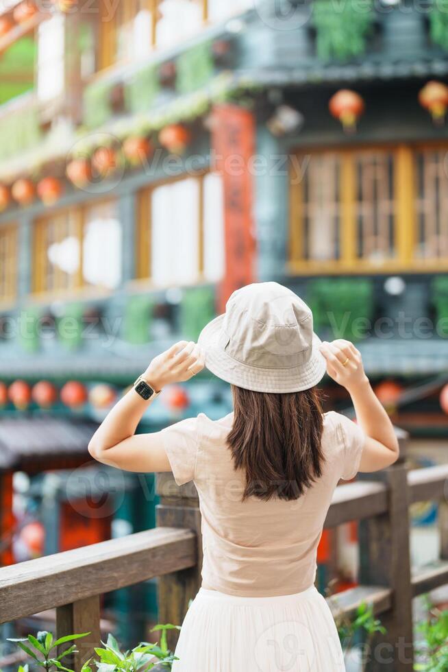 woman traveler visiting in Taiwan, Tourist with hat sightseeing in Jiufen Old Street village with Tea House background. landmark and popular attractions near Taipei city . Travel and Vacation concept photo