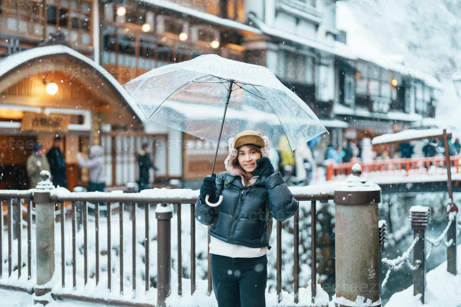 Woman tourist Visiting Ginzan Onsen in Yamagata, happy Traveler sightseeing Japanese Onsen village with Snow in winter season. landmark and popular for attraction in Japan. Travel and Vacation concept photo