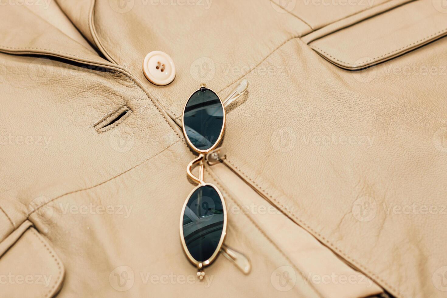 Gold-rimmed sunglasses on the texture of a brown leather jacket, genuine soft leather photo