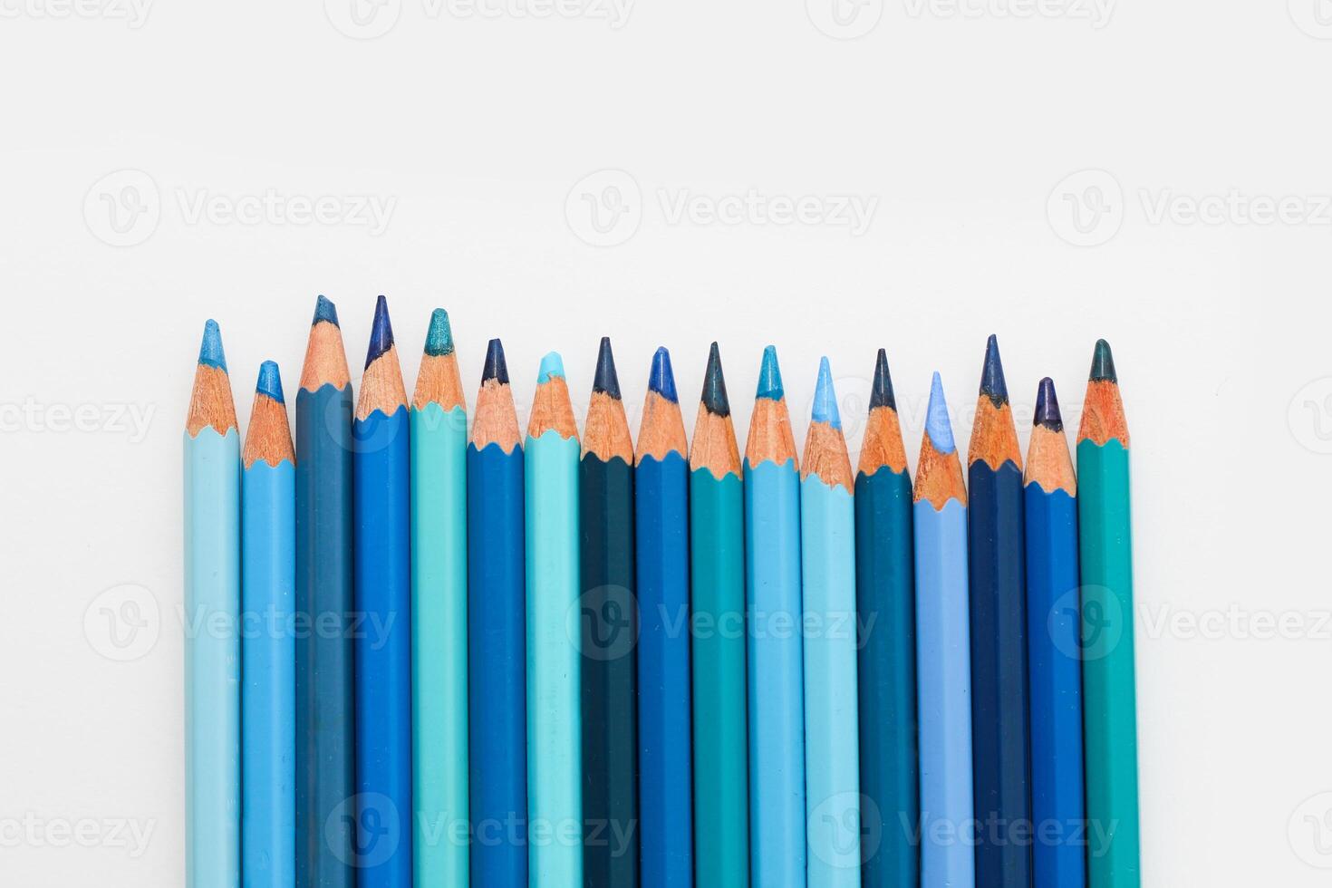 Multi-colored pencils lie on a white table, the blue range of colors photo