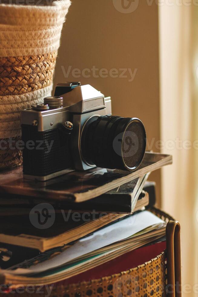 Vintage old camera on a stack of books and magazines in the interior. photo