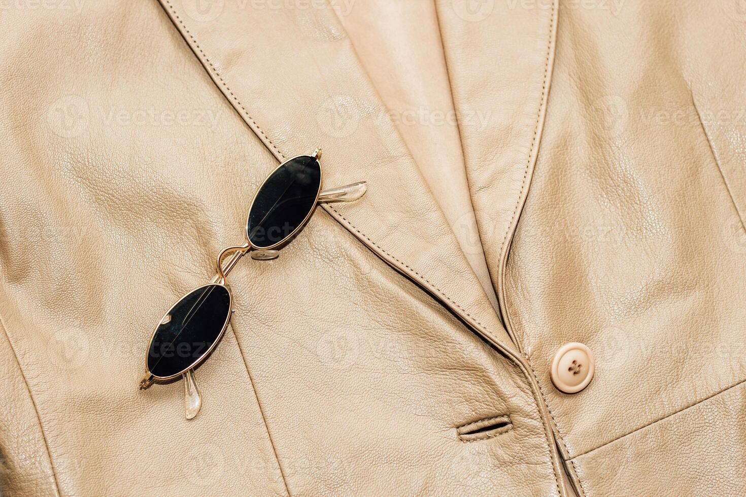 Gold-rimmed sunglasses on the texture of a brown leather jacket, genuine soft leather photo