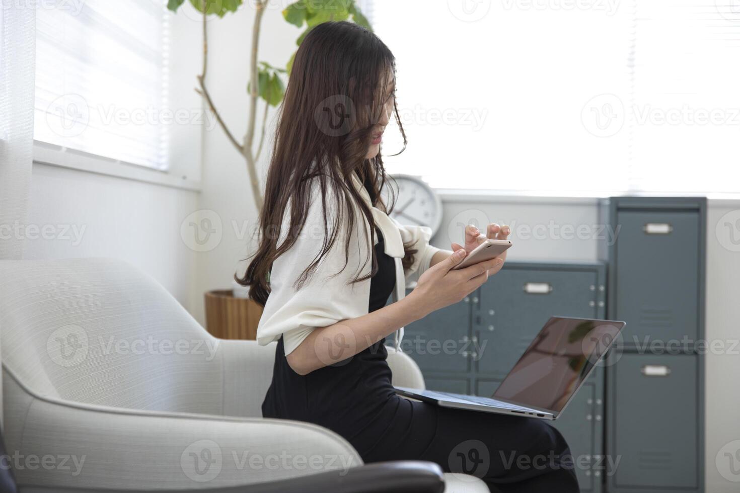 A Japanese woman checking smartphone by remote work in the small office photo