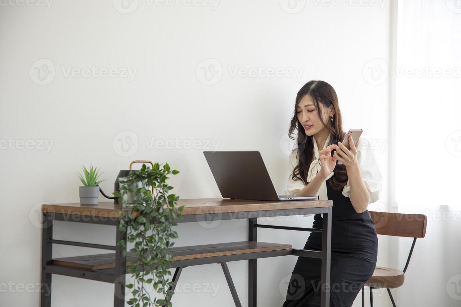 A Japanese woman checking smartphone by remote work in the home office photo