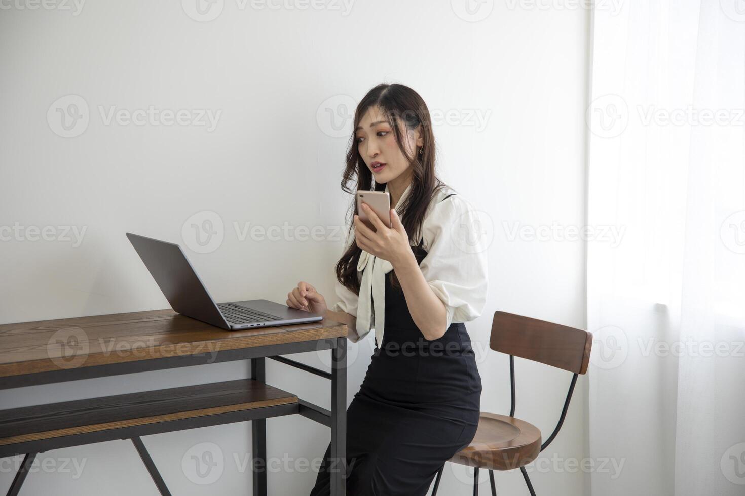 A Japanese woman checking smartphone by remote work in the home office photo