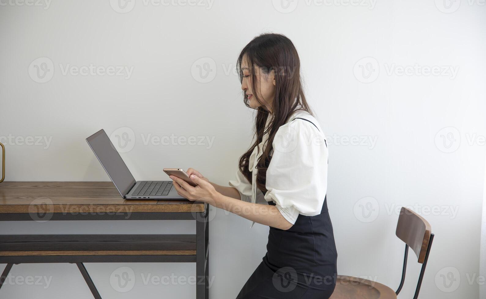 A Japanese woman checking smartphone by remote work in the home office photo