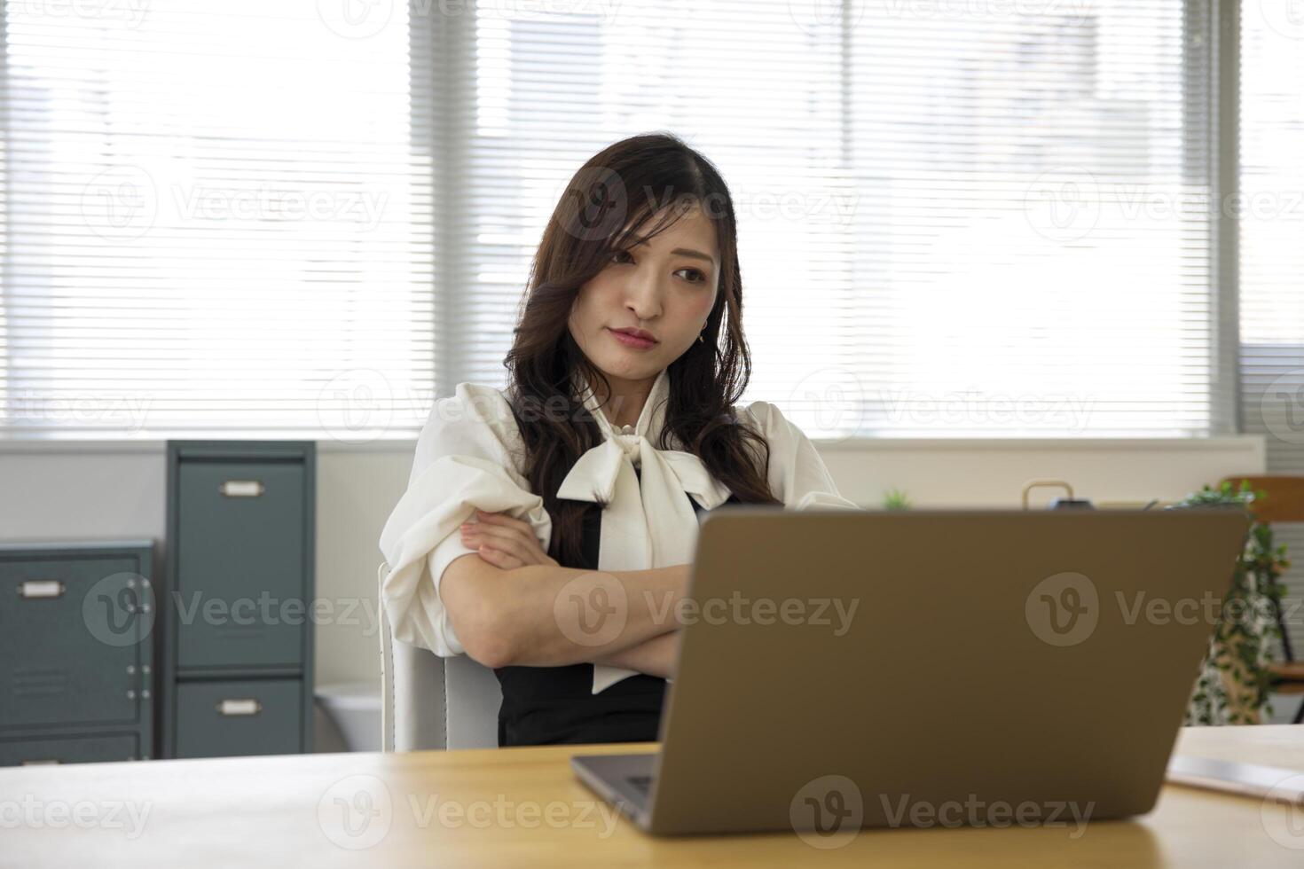un preocupado japonés mujer por remoto trabajo en el pequeño oficina foto