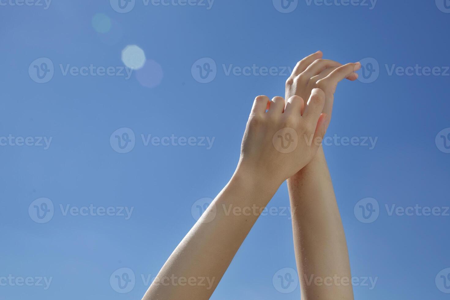 Female hands stretching after waking up to the blue sky . Sunny day . Young hands . Morning wake up .Blue background hands up in the air .selective focus photo