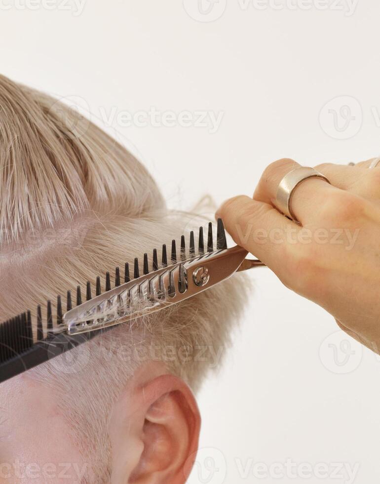 hairdresser hands who cut blonde model hair. selective focus.. High quality photo