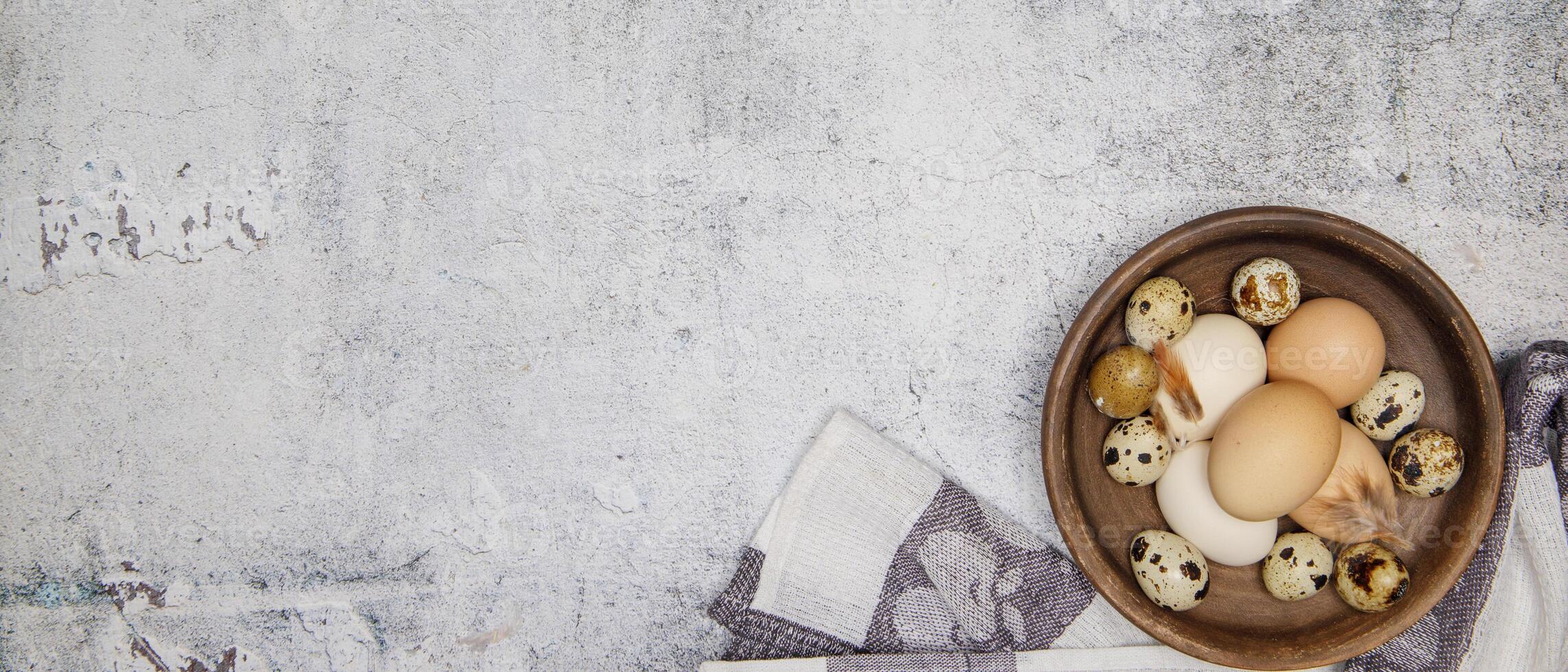 fresh quail and chicken eggs from the farm in a brown clay plate on a gray marble table. selective soft focus. top view .High quality photo