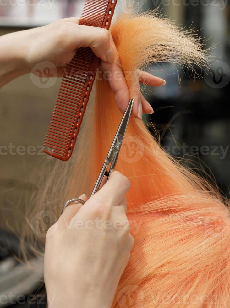 the hands of an invisible hairdresser with a comb and scissors hold a strand of red hair. selective focus.High quality photo