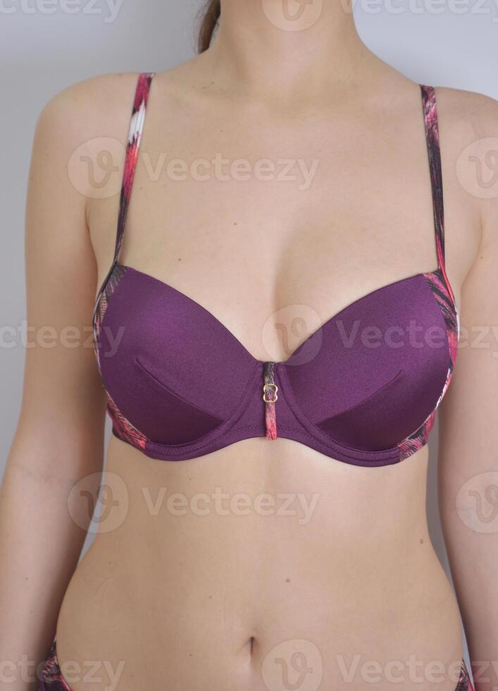 Women's swimming suit. A burgundy plum bra from a bikini swimsuit on a slim model. Women's clothing for the beach and swimming in the water. photo