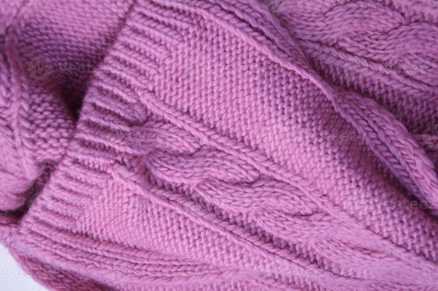 Knitted pink lilac sweater fabric with a beautiful textured pattern. Warm wool scarf. Background. photo