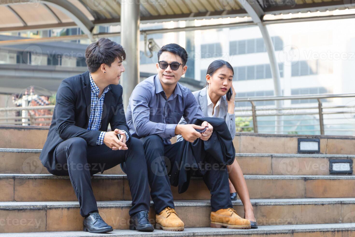 Young businesspeople sitting on stairs with friends, Business people meeting and sharing ideas, Young Asian business team discussing in the morning photo