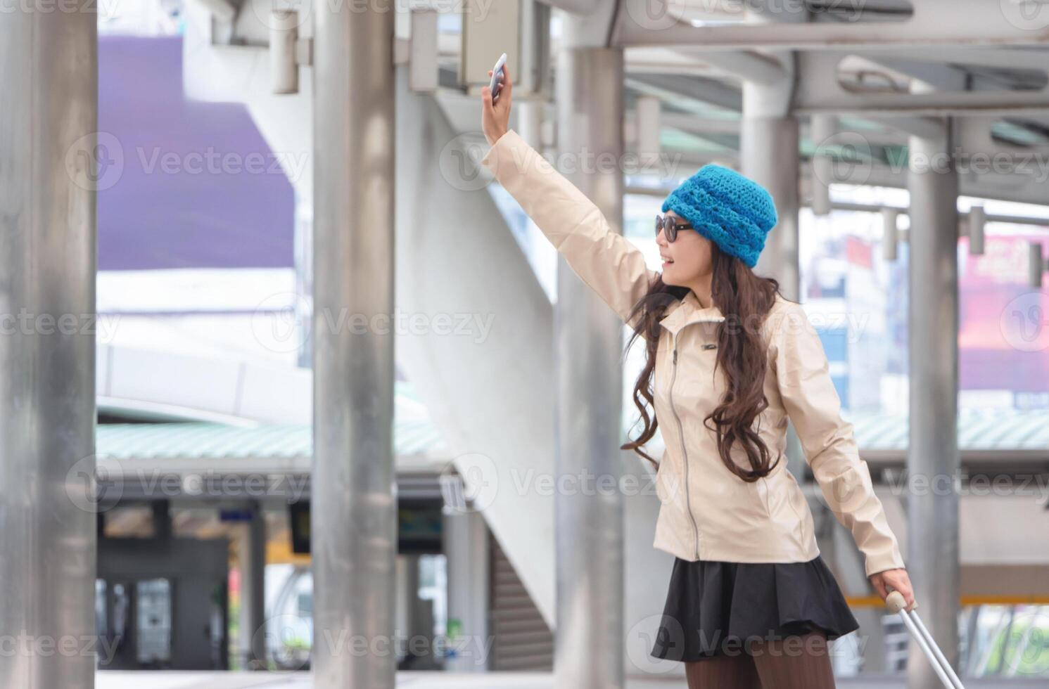 Young female traveler with a suitcase at the modern transport stop outdoors photo