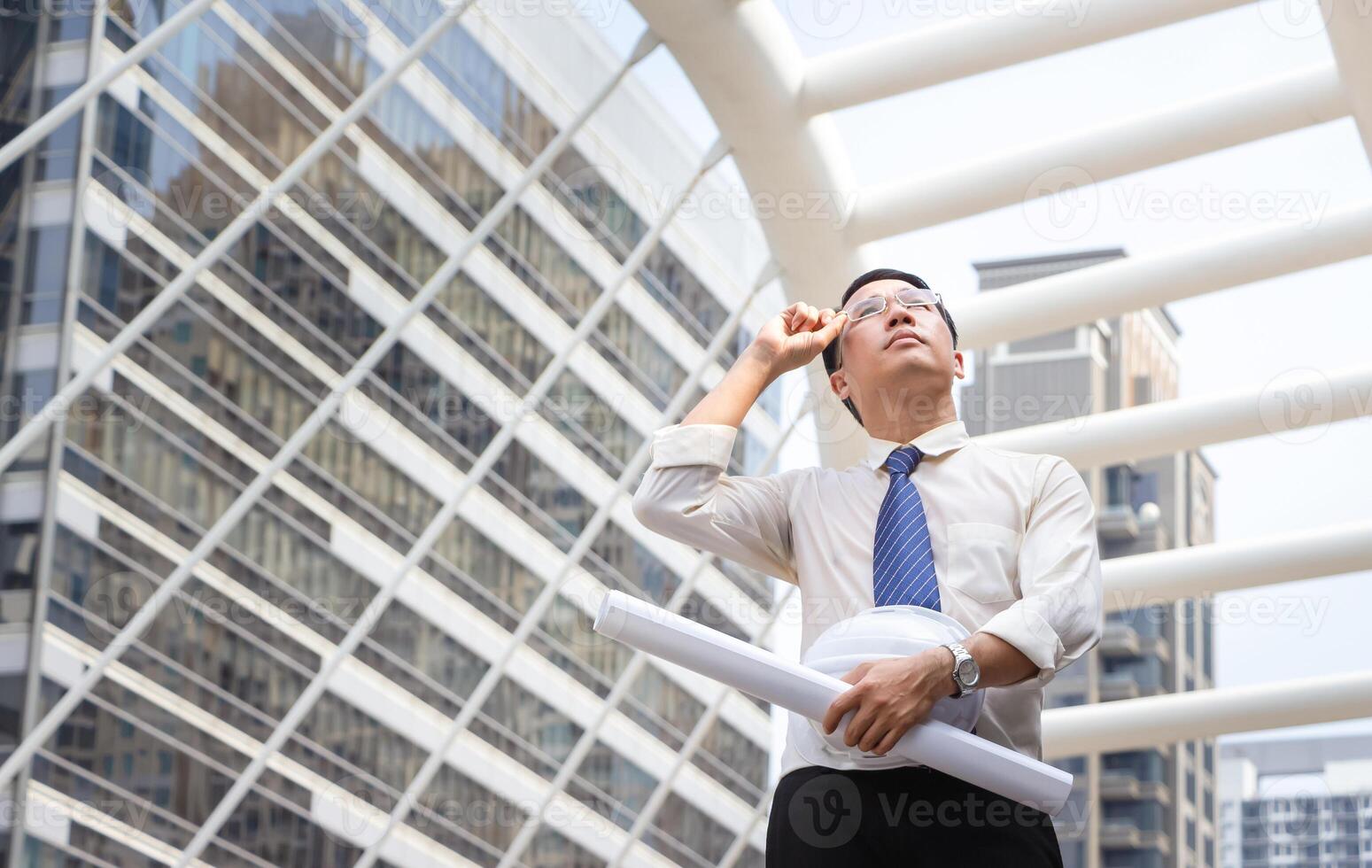 Asian engineer man checking projects at a building site, Foreman worker with hardhat and blueprint on construction site photo