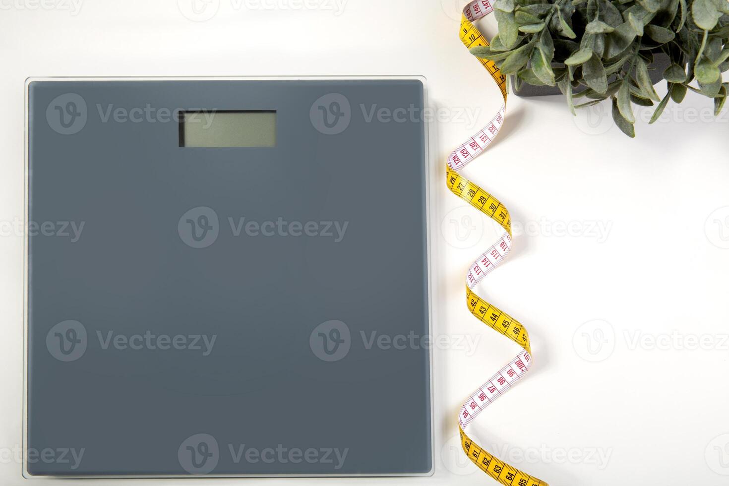 electronic scales and yellow measuring tape on light background with copy space. Close up. View from above. High quality photo