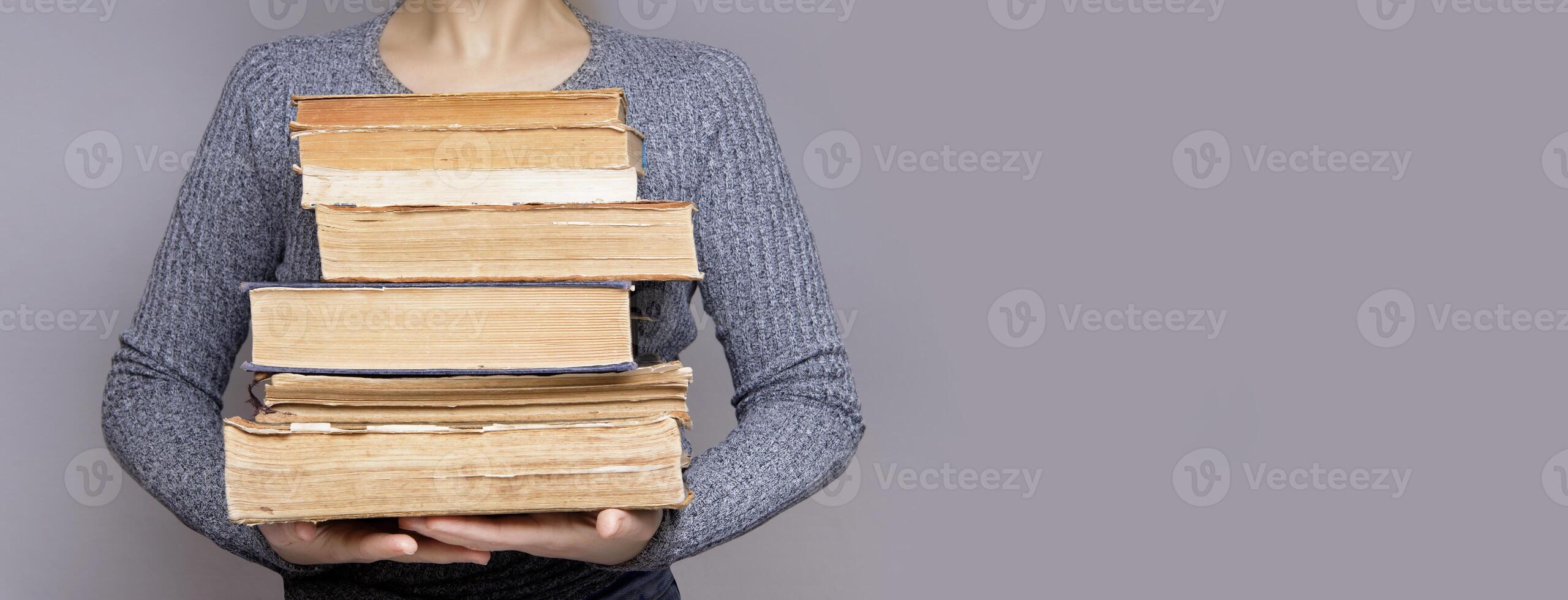 young female student looking and smiling looking at a book. holds many old books in her hands.Banner.learning and knowledge concept photo