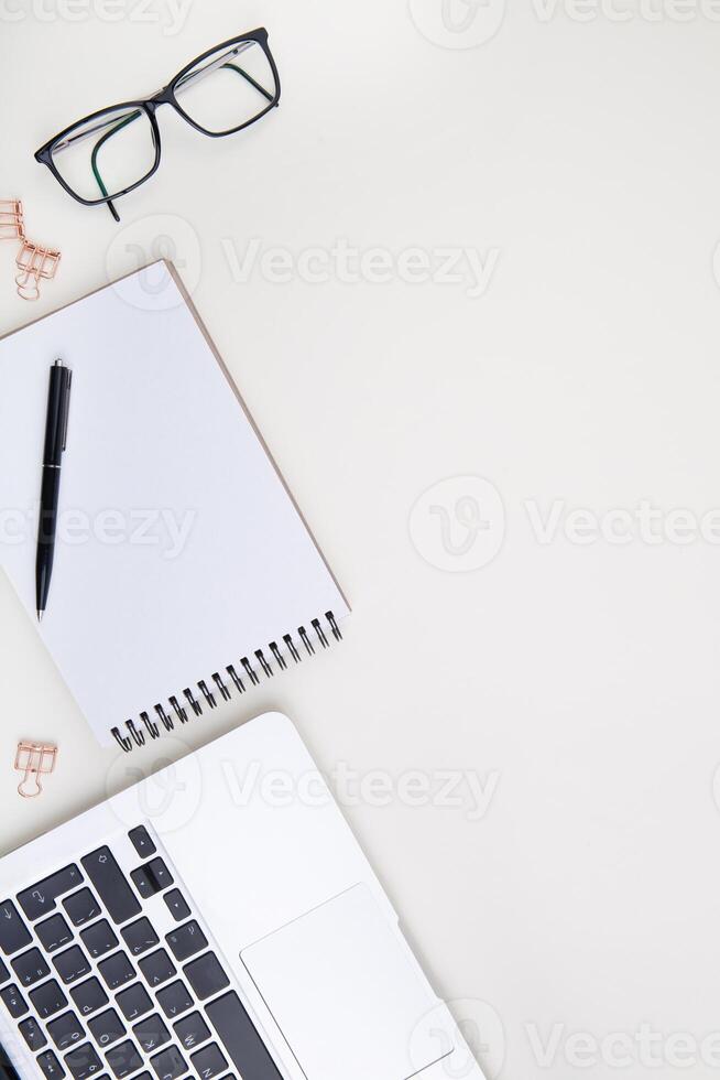 light office desk with laptop, white notebook mockup and glasses . Top view with copy space for text input. High quality photo. photo