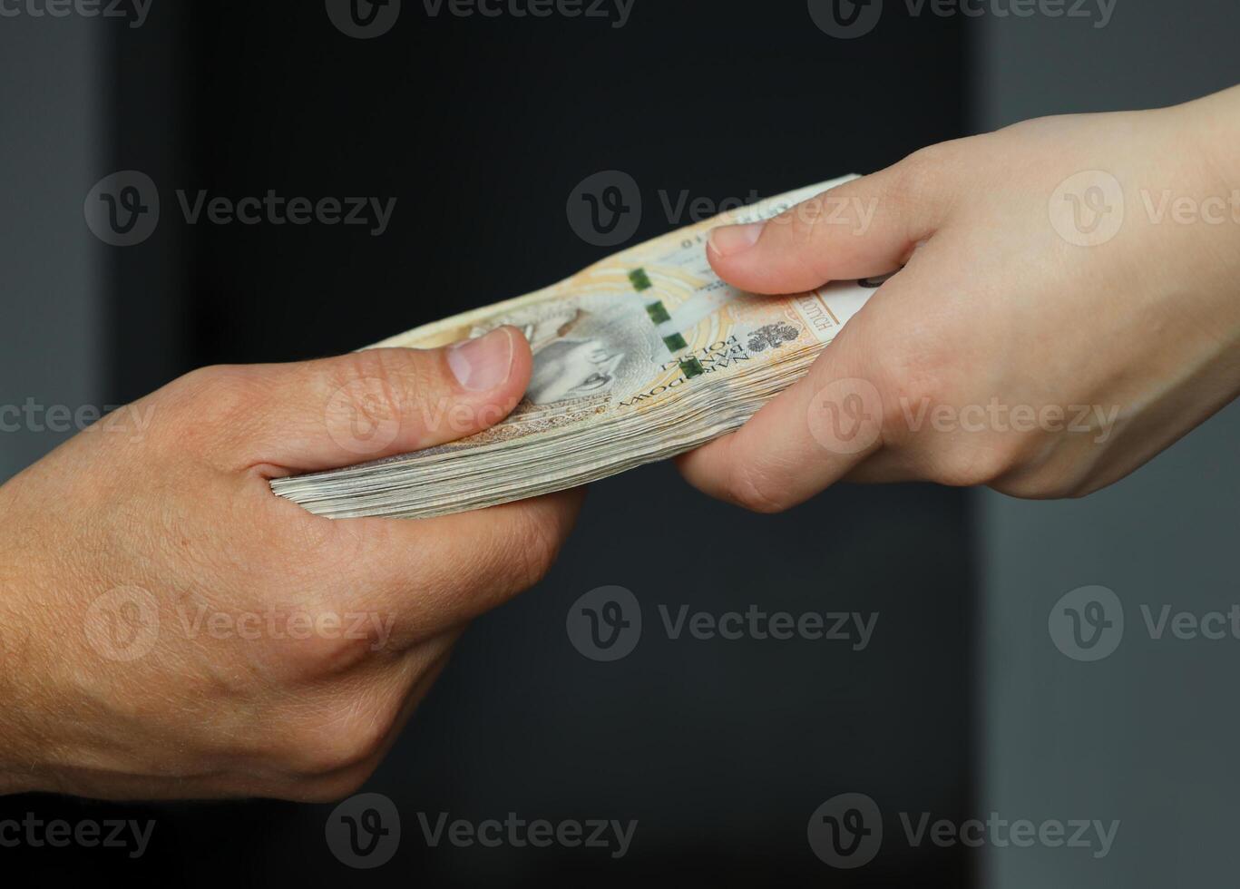 male and female hands holding a bundle of 200 zloty banknotes. selective focus photo