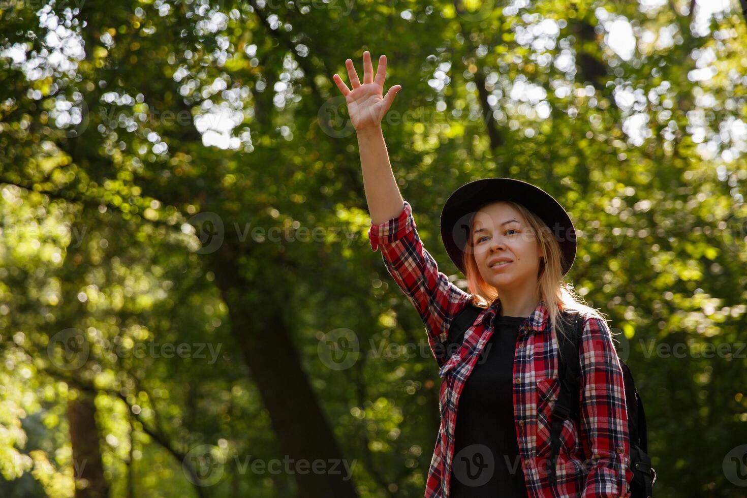 young caucasian woman in a hat waving in greeting. blurred background, selective focus. High quality photo