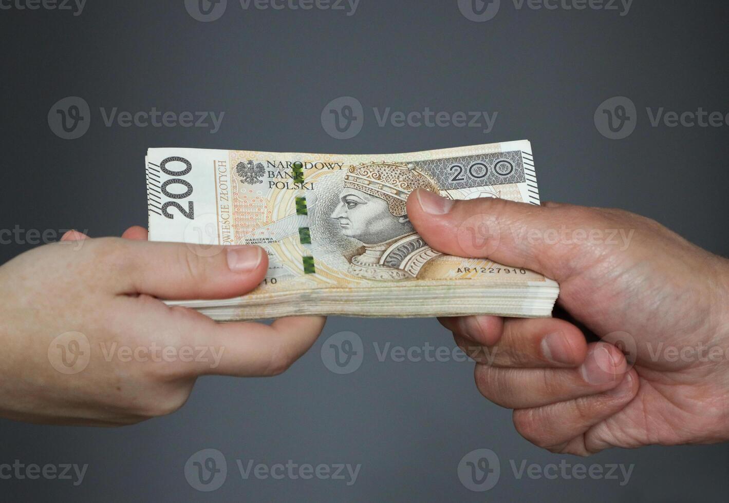 male hand giving a bundle of large banknotes to female hands. selective focus photo